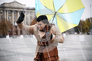 Man with colorful umbrella caught in gust of wind on street