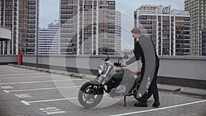 Man comes to motorbike and wears helmet on top of the multi-level parking