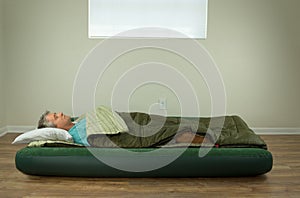 Man comfortably sleeping on blow up air mattress bed in sleeping bag