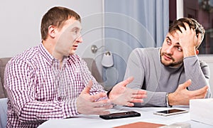 Man comforting upset friend at home table
