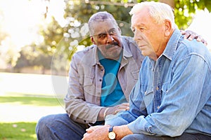 Man Comforting Unhappy Senior Friend Outdoors