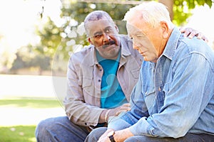 Man Comforting Unhappy Senior Friend Outdoors