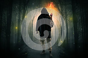 Man coming from dark forest with burning flambeau in his hand concept