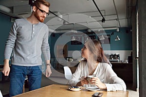 Man coming to cafe table getting acquainted with beautiful woman