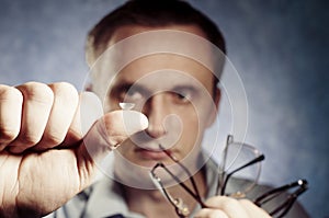 Man is comparing contact lens with glasses