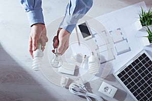 Man comparing an incandescent bulb and a CFL lamp photo