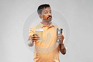 Man comparing thermo cup or tumbler and coffee cup