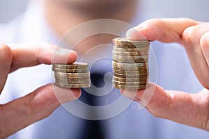 Man Comparing Two Coin Stacks