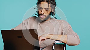 Man composing email, typing on laptop keyboard, studio background