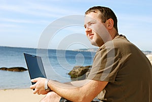 Man with computer at beach