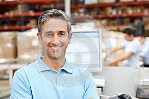 Man At Computer Terminal In Distribution Warehouse