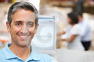 Man At Computer Terminal In Distribution Warehouse