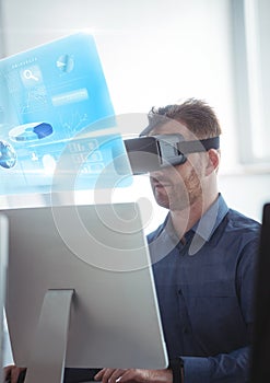 Man on computer wearing VR Virtual Reality Headset with Interface