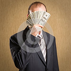 Man concealing his face with a fistful of money