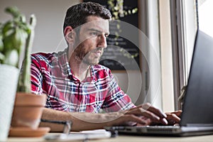 Man concentrating on work and typing on laptop