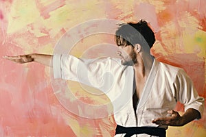 Man with confident face and bristle on colorful background. Karate fighter with fit strong body practices martial arts.