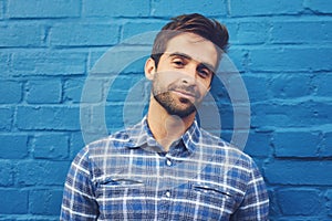 Man, confident in portrait and relax on wall background, casual fashion and positivity with blue aesthetic. Cool smirk