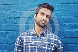 Man, confident in portrait and relax on wall background, casual fashion and positivity with blue aesthetic. Cool smirk photo
