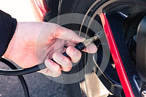 Man connecting air compressor to car tires