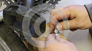 A man connects the links of a bicycle chain. Hammers the pin with a hammer. Bicycle repair. Close-up
