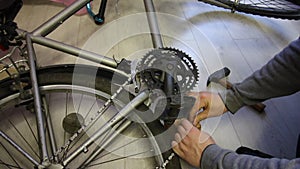 A man connects the links of a bicycle chain. Hits the pin with a hammer. Bicycle repair