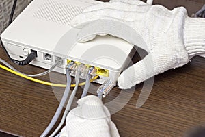 A man connects a network cable to the modem, a close-up network