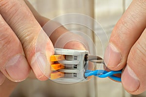 Man connects the twisted ends of the wires using compact splicing connector