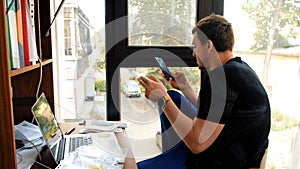 Man considers paper smartphone and laptop