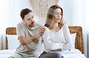 Man consoles an offended woman in interior at bedroom. photo