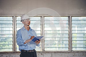 Man construction engineer writing note wear blue shirt safety white hard hat at construction site. Industry labour male worker.