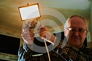 A man at a construction site demonstrates a lantern that he uses to illuminate the place of work