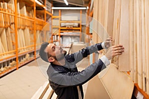 a man in a construction supermarket chooses plywood and boards for construction, housewarming concept and construction