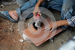 Man construction worker cutting tile with electric