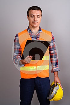 Man construction worker holding clipboard against gray backgroun