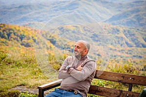 Man Contemplating Nature's Splendor: Sitting on Bench Amidst Majestic Mountain Scenery