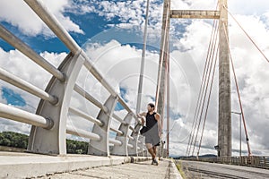 Man contemplating the view from a large bridge with tension cables in the green gulf of Costa Rica in Guanacaste