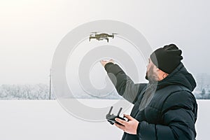 Man control drone and landing quadcopter on his hand at white winter background