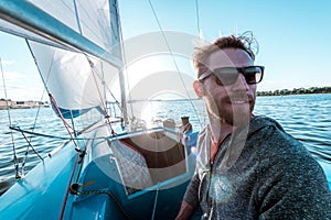 Man controls boat using tiller at stern during sailing on river at summer day