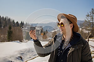 Man controls the flying drones in snowy forest winter. Adventurous winter holiday