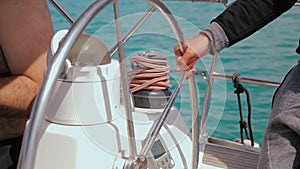Man controls the steering wheel of a sailing boat