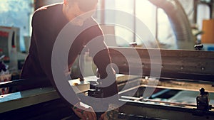 Man controls wide industrial printer in workshop