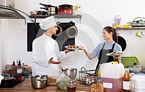 Man cook giving to waitress ready to serve salad