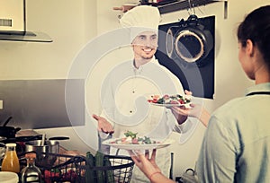 Man cook giving to waitress ready to serve salad