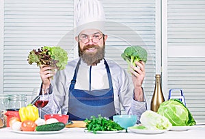 Man cook hat and apron hold broccoli. Organic vegetables. Healthy nutrition concept. Bearded professional chef cooking