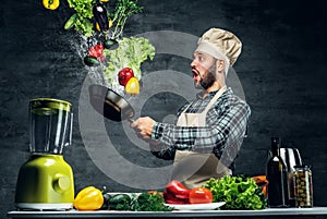 Man cook holds a pan with vegetables flying in the air.