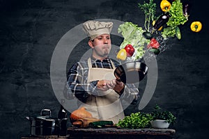 Man cook holds a pan with vegetables flying in the air.