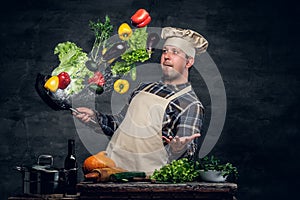 Man cook holds a pan with vegetables flying in the air.