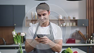 Man cook looking recipe on mobile phone at home kitchen. Chef planning new dish