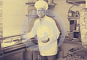 Man cook making kebab dish on kitchen in fast food restaurant