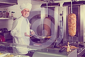 Man cook making kebab dish on kitchen in fast food restaurant